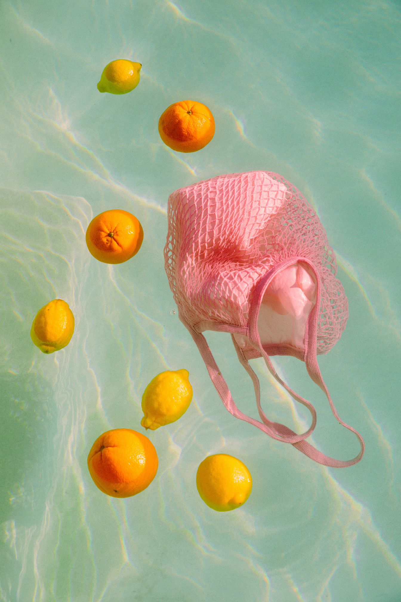 Cotton Mesh Bag with Lemons Floating in Pool